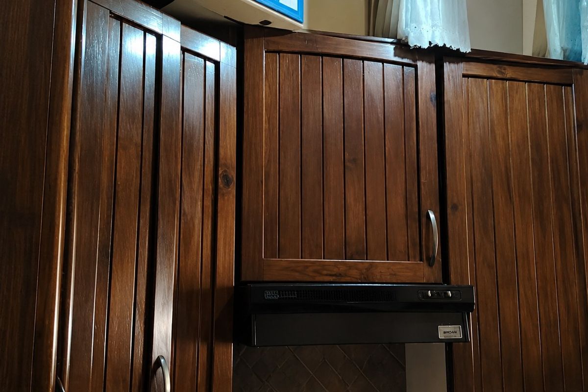 A close-up view of dark wood kitchen cabinetry featuring vertical panel detailing and an integrated extractor fan.
