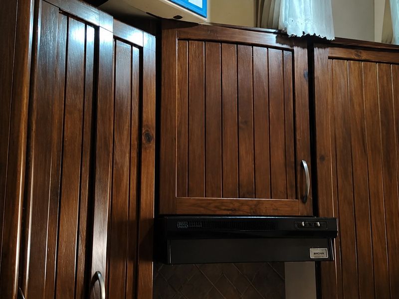 A close-up view of dark wood kitchen cabinetry featuring vertical panel detailing and an integrated extractor fan.