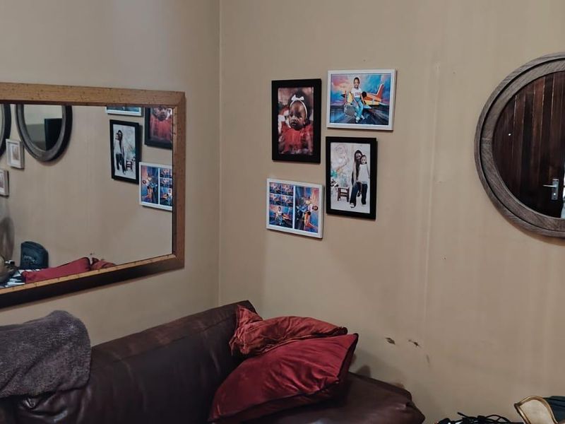 A living room area featuring wall-mounted mirrors and decorative wall art, showing signs of wear on the wall surfaces.