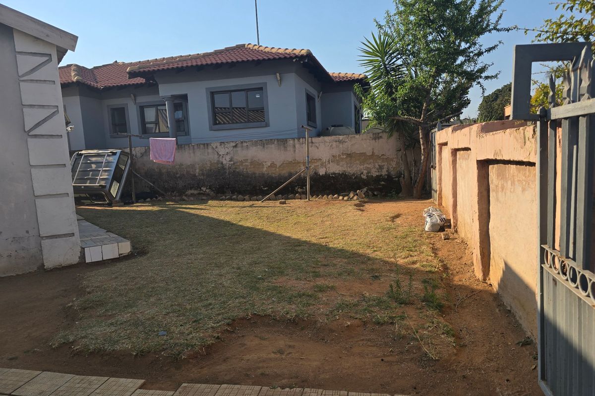 Rear garden area featuring a lawn, perimeter wall, and paved section, offering potential for landscaping and outdoor improvement.