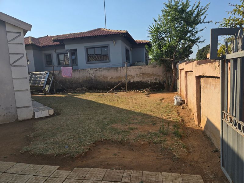 Rear garden area featuring a lawn, perimeter wall, and paved section, offering potential for landscaping and outdoor improvement.