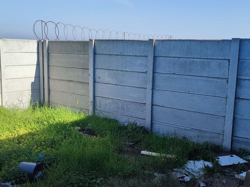 A rear garden area featuring a precast concrete boundary wall topped with security razor wire.