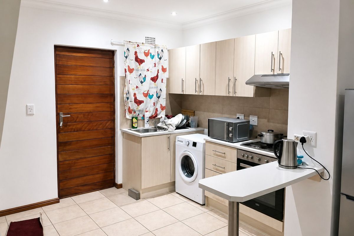 A functional kitchen featuring light wood cabinetry, tiled flooring, built-in oven and hob, and a convenient breakfast bar counter.