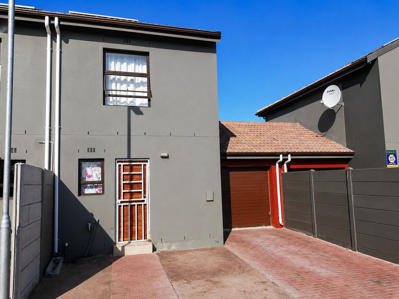 Front elevation of a double-story residential property featuring a paved driveway, integrated garage, and secure entrance with security gate.