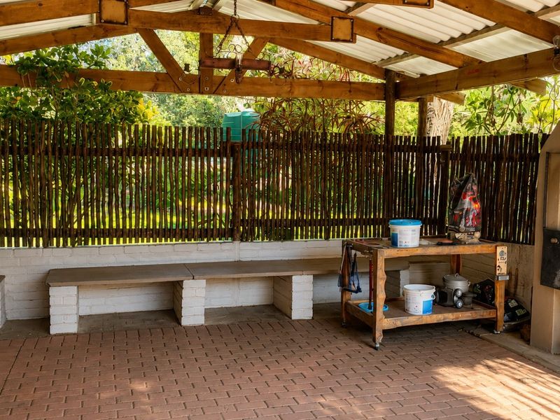 Covered outdoor patio area featuring a built-in brick braai, paved flooring, and integrated bench seating, ideal for outdoor entertaining.