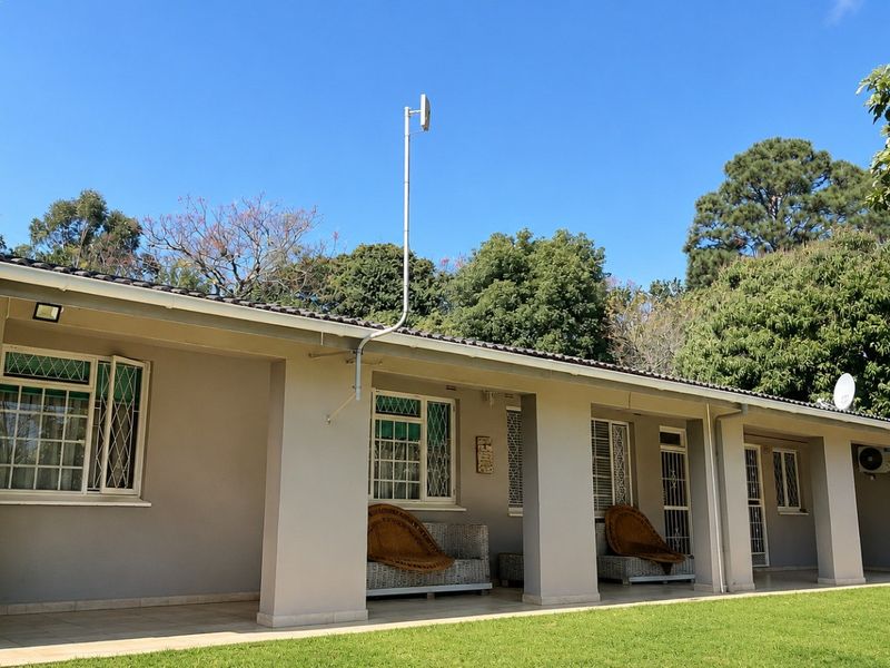 A spacious covered patio area featuring tiled flooring, security bars on windows, and direct access to the garden.