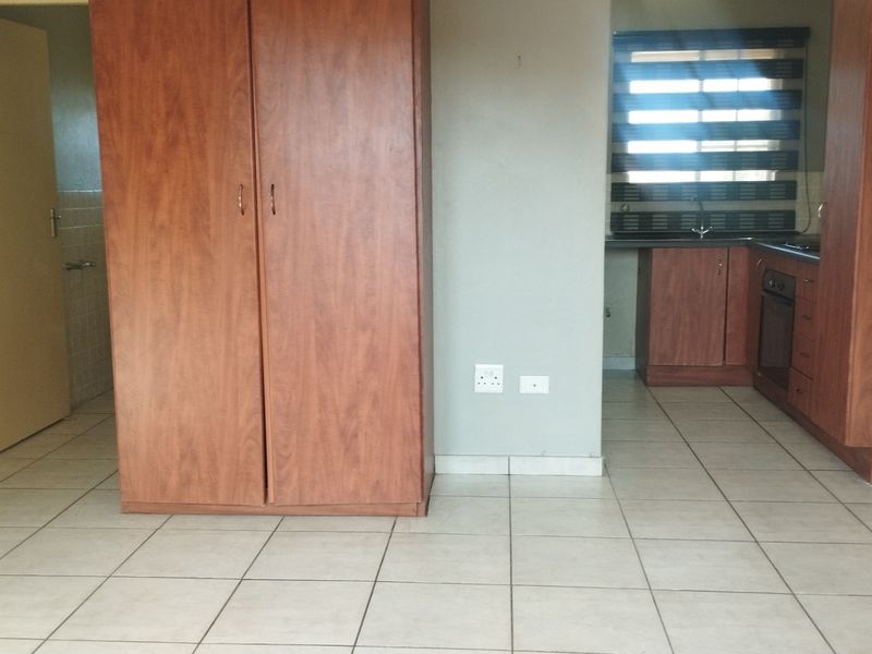 Open plan living area featuring tiled flooring, built-in storage cupboards, and a functional kitchen with fitted cabinetry and built-in oven.