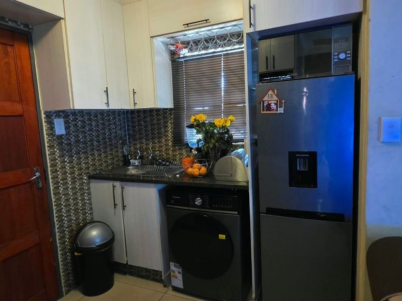 Compact kitchen area featuring built-in cabinetry, a mosaic tile backsplash, and integrated appliance space.