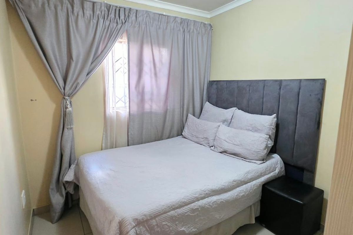 A compact bedroom featuring neutral wall finishes, a window with security bars, and coving detail.