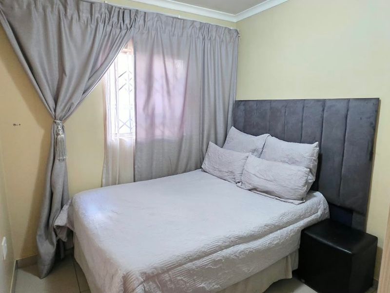 A compact bedroom featuring neutral wall finishes, a window with security bars, and coving detail.