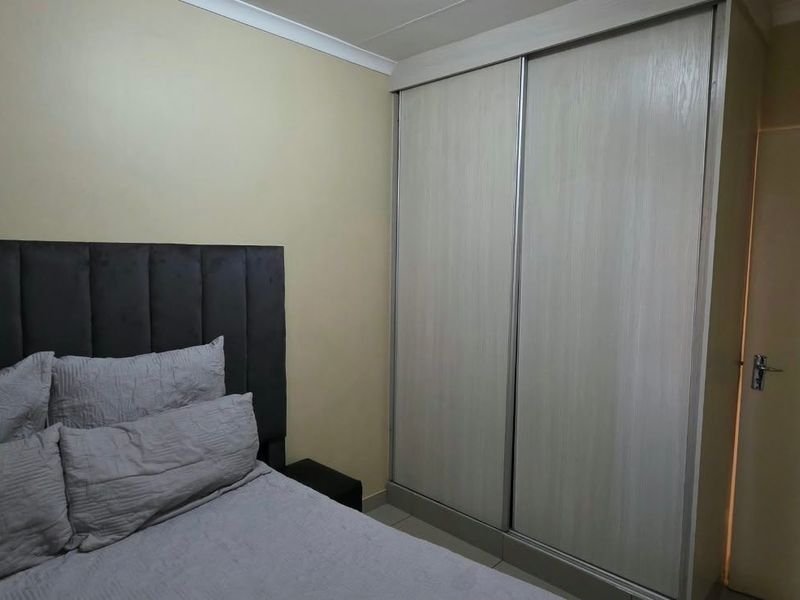 A bedroom featuring a built-in sliding door wardrobe and neutral wall finishes.