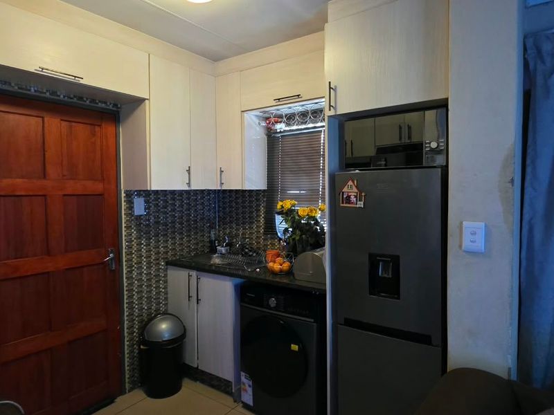 A compact kitchen area featuring built-in cabinetry, a tiled backsplash, and integrated appliances, providing a functional workspace.