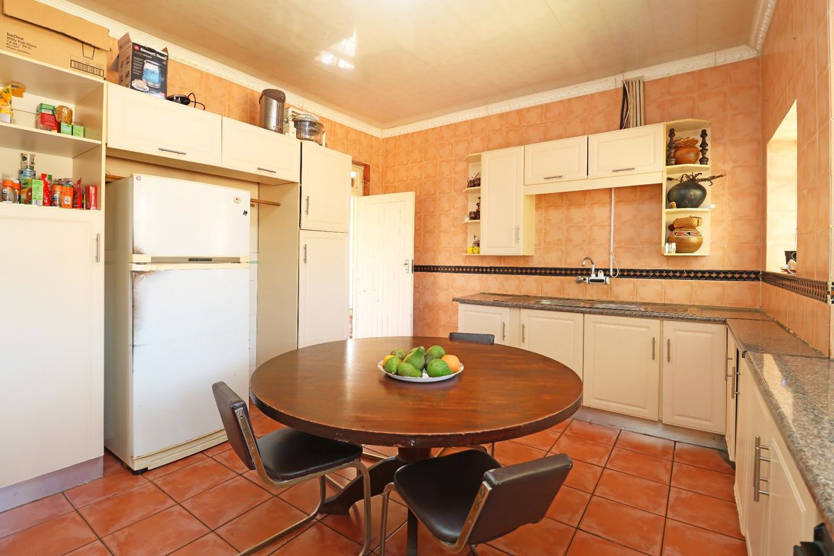 A dated kitchen featuring built-in cabinetry, granite countertops, and tiled finishes, offering potential for a modern renovation to enhance the space's functionality and aesthetic.