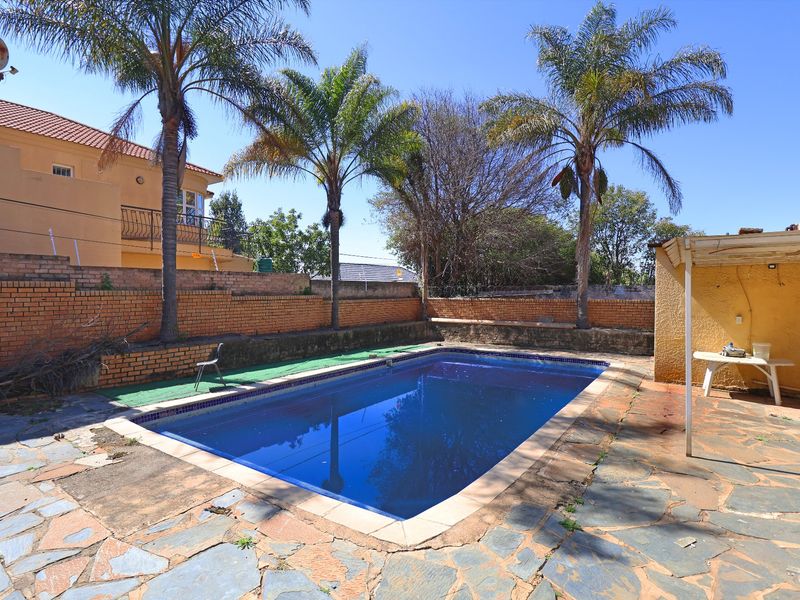 Outdoor pool area featuring a swimming pool, stone paving, and brick boundary walls, offering potential for landscaping and entertainment space upgrades.