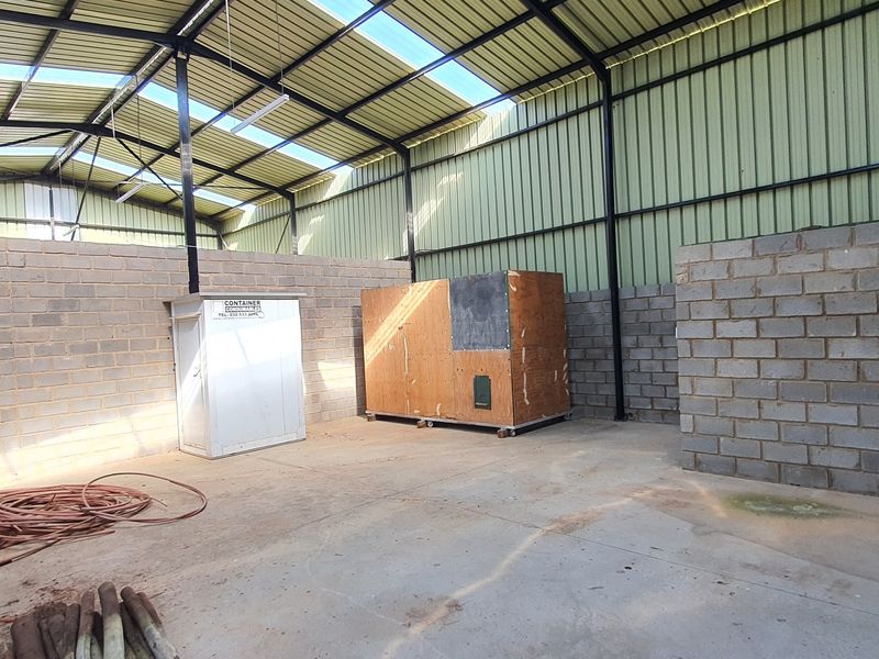 Spacious industrial utility area featuring concrete block walls, a high-clearance corrugated metal roof with skylights, and a durable concrete floor.