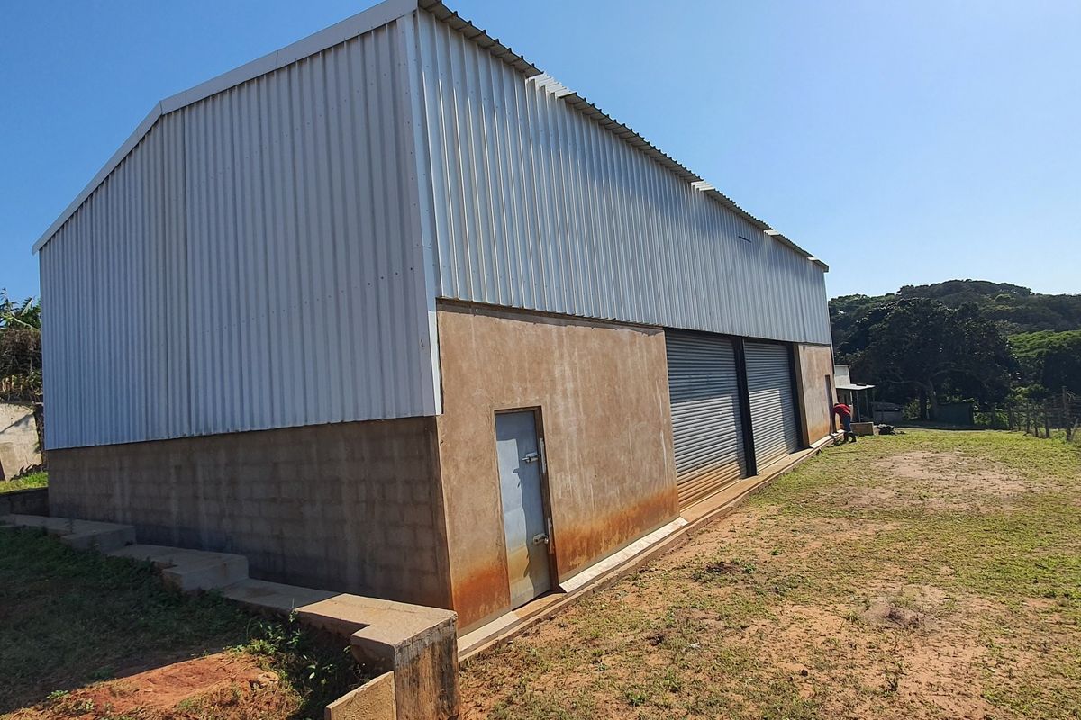 Exterior view of an industrial warehouse featuring corrugated metal cladding, concrete block walls, and multiple roller shutter doors.