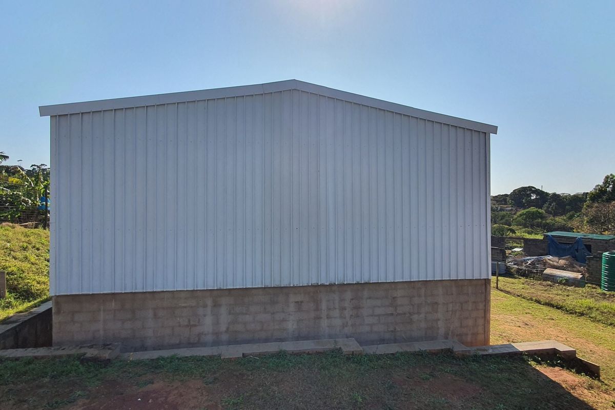 Rear view of an industrial structure featuring corrugated metal cladding over a concrete block foundation base.