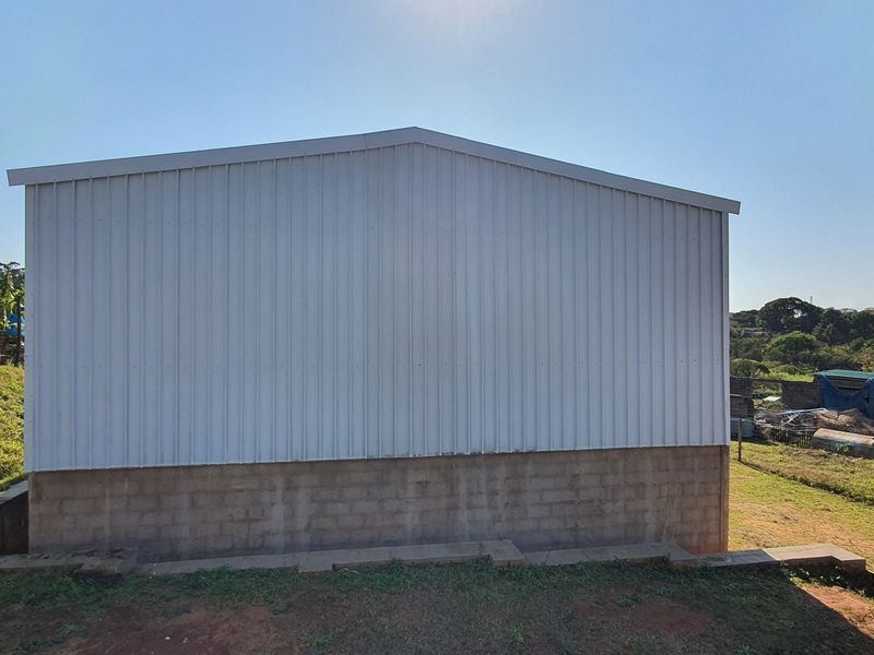 Rear view of an industrial structure featuring corrugated metal cladding over a concrete block foundation base.
