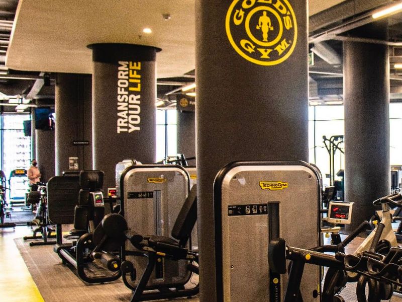 A well-equipped commercial gym facility featuring structural columns, recessed lighting, and professional-grade exercise equipment.