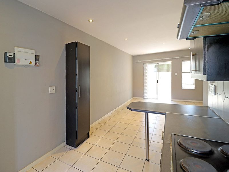 Open-plan kitchen and living area featuring tiled flooring, built-in cabinetry with integrated appliances, and sliding door access to the exterior.