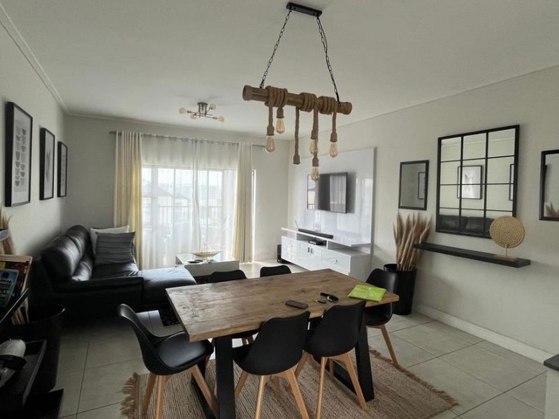 Open plan living and dining area featuring tiled flooring, a built-in media console, and access to an outdoor balcony through sliding glass doors.