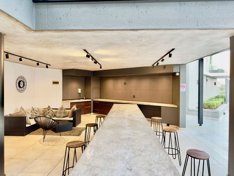 Modern open-plan entertainment area featuring a large concrete breakfast bar, built-in cabinetry, and sleek track lighting, perfect for social gatherings.
