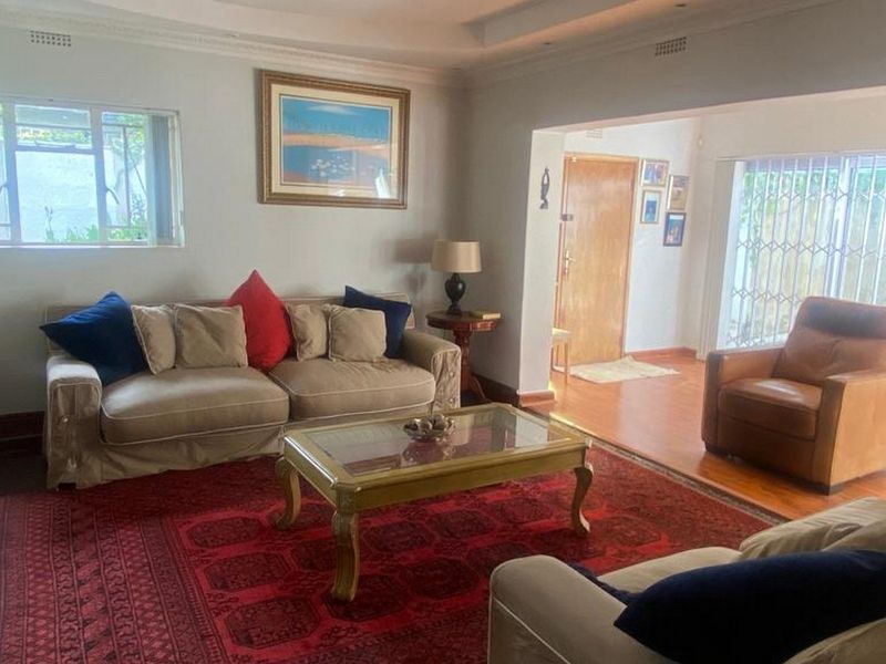 Spacious living room featuring laminate flooring, a stone fireplace surround, and direct access to the exterior through a sliding door with security gate.