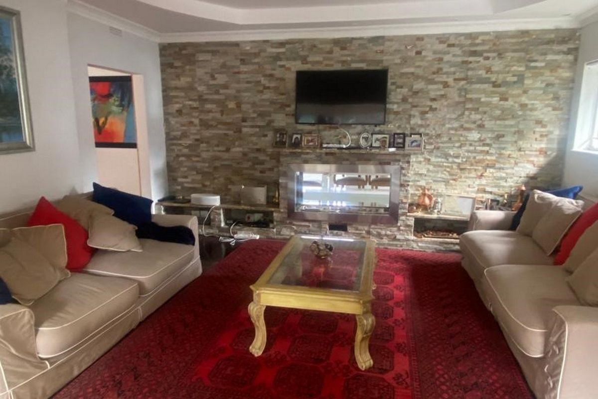 Spacious living room featuring a prominent stone-clad feature wall with a built-in fireplace and elegant recessed ceiling detailing.