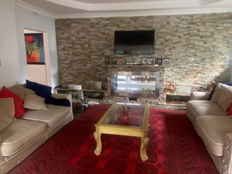 Spacious living room featuring a prominent stone-clad feature wall with a built-in fireplace and elegant recessed ceiling detailing.