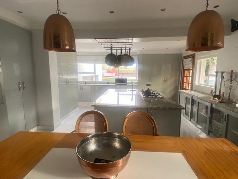 Spacious open-plan kitchen featuring a central island with granite countertops, modern cabinetry, and stylish pendant lighting, creating a functional and inviting culinary space.