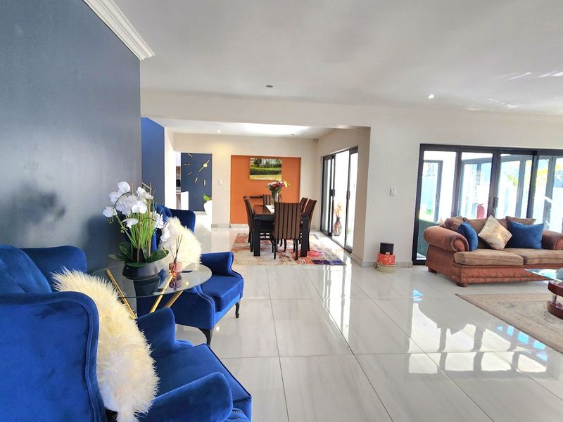 Spacious open-plan living and dining area featuring polished porcelain floor tiles, recessed lighting, and large sliding glass doors leading to the outdoor space.