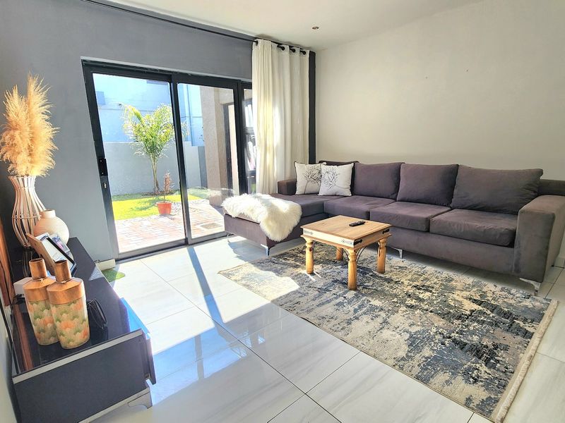 A bright living room featuring large sliding glass doors that provide direct access to the outdoor patio area and natural light.