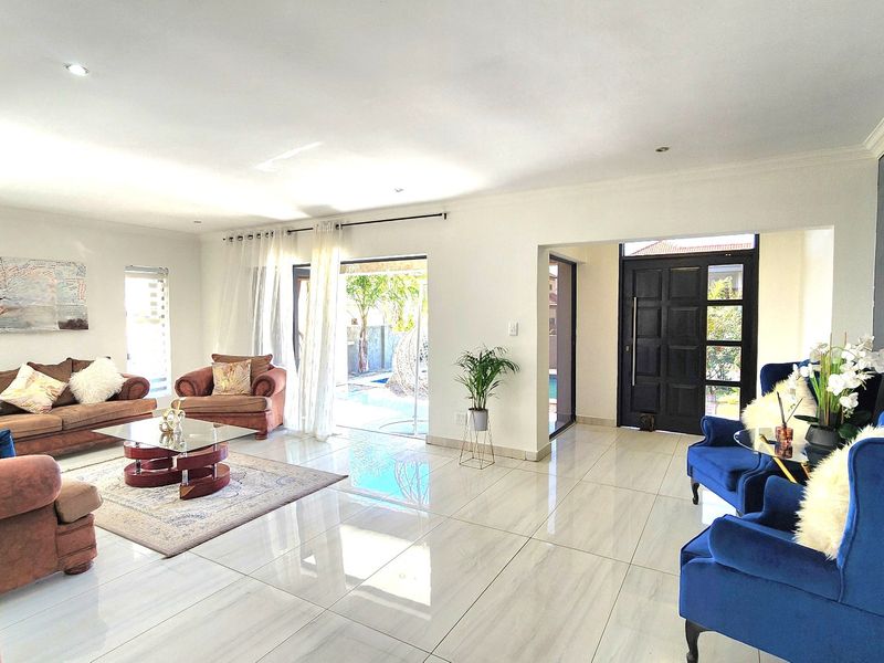 Spacious open-plan living area featuring polished porcelain floor tiles, recessed downlighting, and direct access to the outdoor patio area through sliding glass doors.