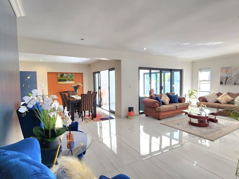 Spacious open-plan living and dining area featuring polished porcelain floor tiles, recessed lighting, and large sliding glass doors providing seamless access to the outdoors.