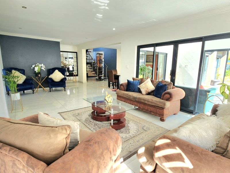 Spacious open-plan living area featuring large sliding glass doors, polished tile flooring, and recessed lighting, with a view toward the staircase.