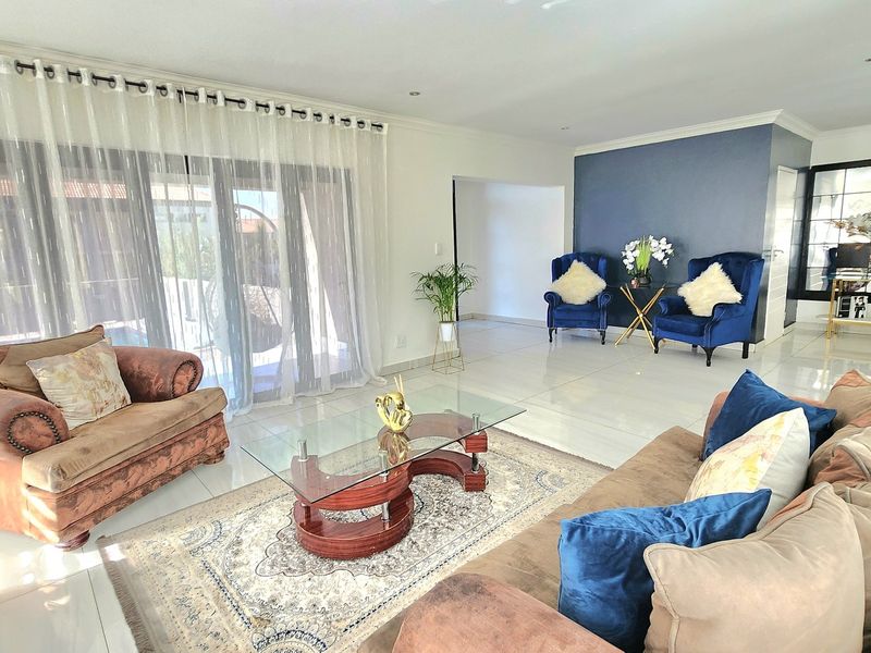 Spacious living room featuring polished tiled flooring, recessed lighting, and large sliding glass doors that provide ample natural light and access to the outdoors.