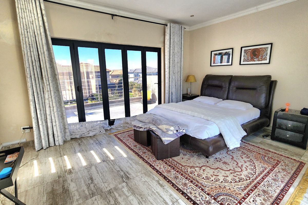 Spacious bedroom featuring tiled flooring and large stacking doors that open onto an outdoor balcony area.