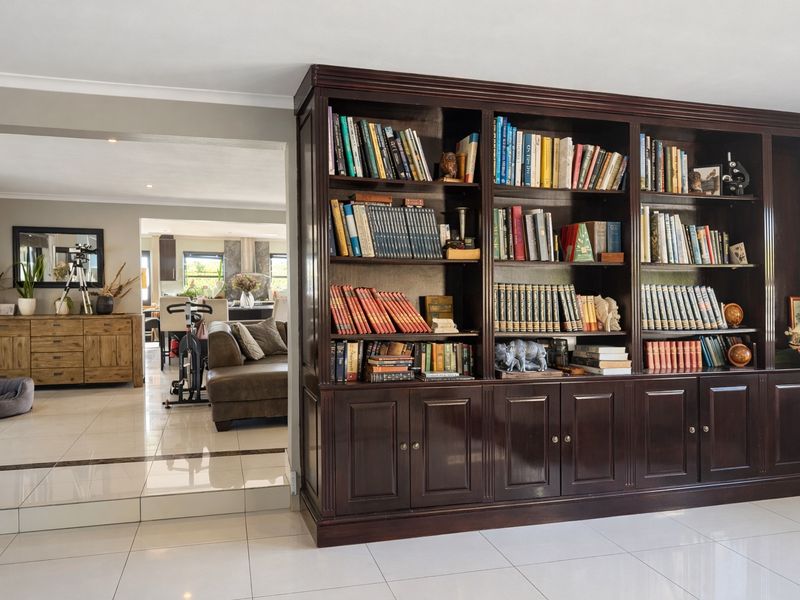 Spacious living area featuring large built-in dark wood cabinetry and polished light-colored floor tiles, with an open-plan flow to the adjacent dining space.