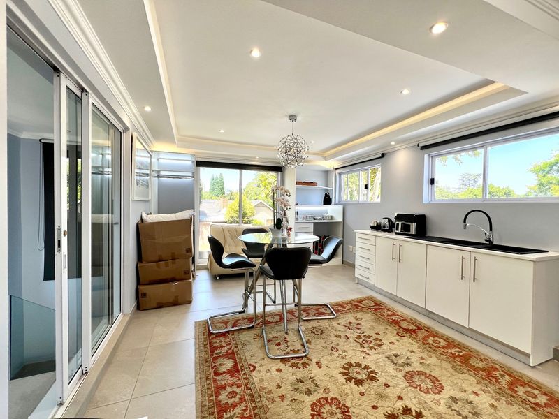 Modern open-plan living and kitchen area featuring sleek white cabinetry, recessed ceiling lighting, and large sliding glass doors leading to an outdoor space.