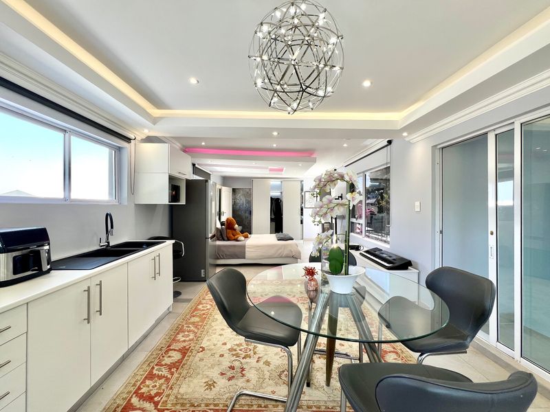 Modern open-plan apartment featuring a sleek kitchen, recessed ceiling lighting, and sliding glass doors leading to an outdoor area.