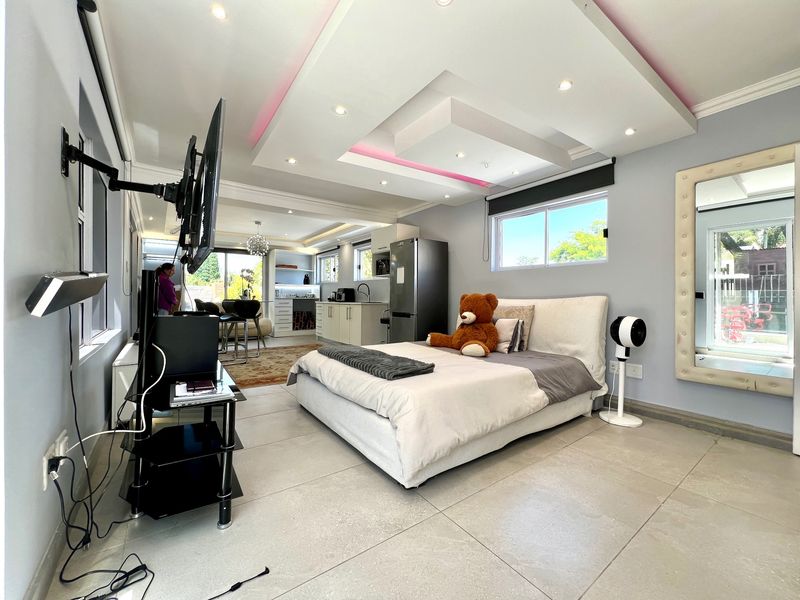 Spacious open-plan studio apartment featuring a modern recessed ceiling with ambient lighting, tiled floors, and an integrated kitchen area with contemporary cabinetry.