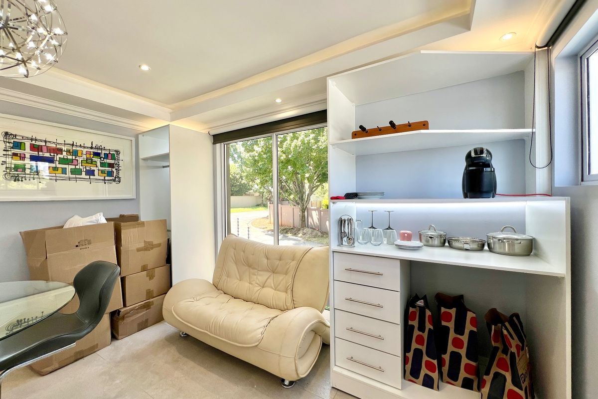 A bright living area featuring modern recessed ceiling lighting, tiled floors, and custom built-in cabinetry with integrated shelving and drawers.