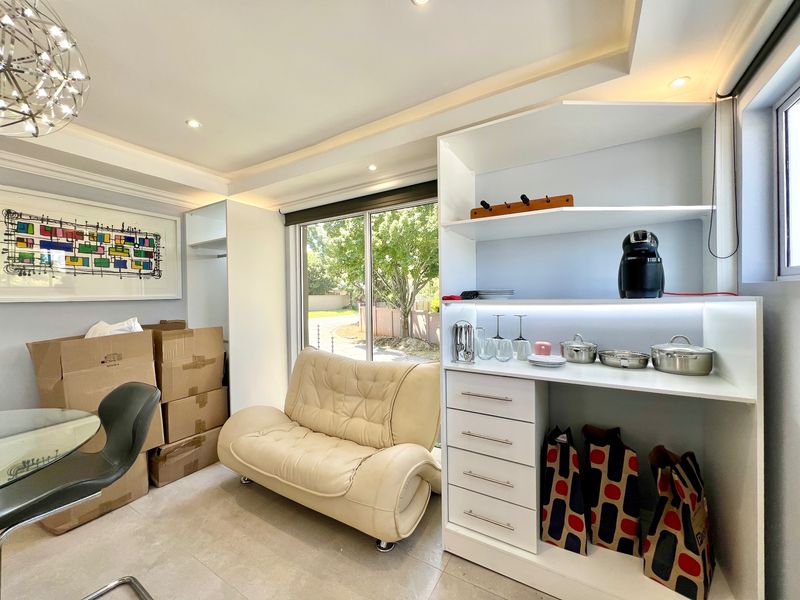 A bright living area featuring modern recessed ceiling lighting, tiled floors, and custom built-in cabinetry with integrated shelving and drawers.