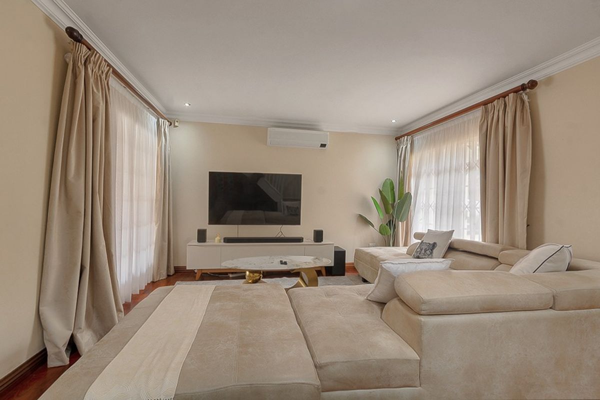 A comfortable living room featuring timber flooring, recessed downlighting, and a wall-mounted split-system air conditioner.