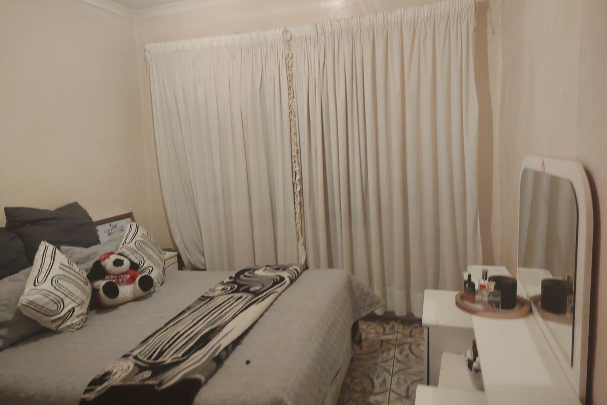A bedroom featuring tiled flooring and window curtains.