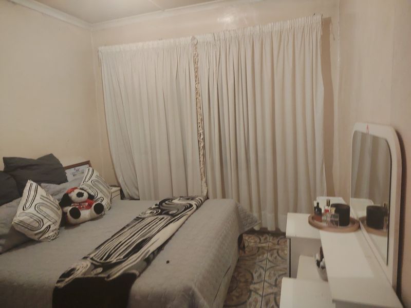 A bedroom featuring tiled flooring and window curtains.