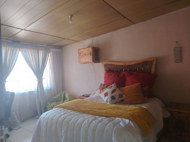 A bedroom featuring a timber ceiling and a built-in wall cabinet, showing signs of wall cracking that may require maintenance.