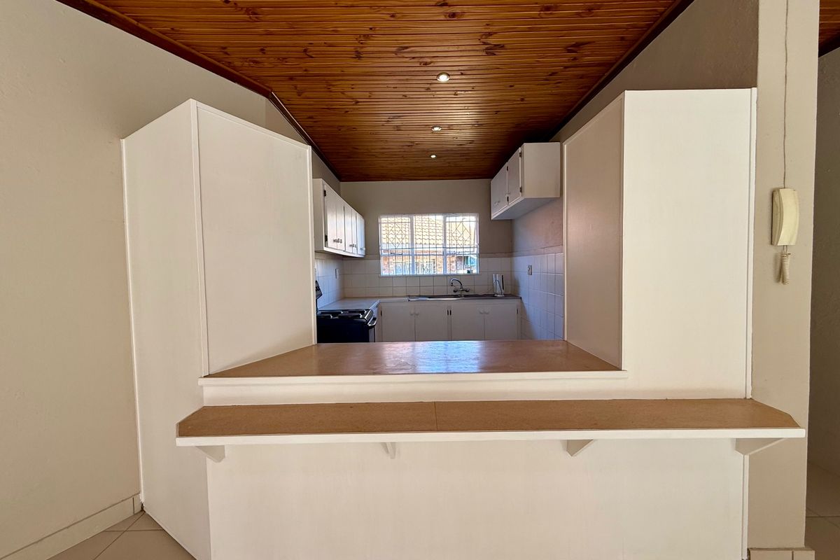 A functional kitchen featuring a timber ceiling, built-in cabinetry, and a breakfast bar, offering a practical layout ready for modern updates.