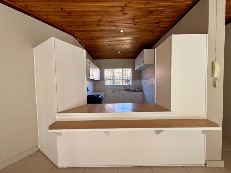 A functional kitchen featuring a timber ceiling, built-in cabinetry, and a breakfast bar, offering a practical layout ready for modern updates.
