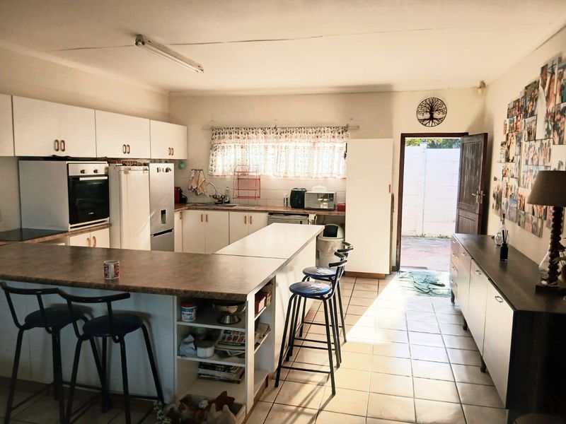 Open-plan kitchen featuring laminate countertops, built-in oven, and tiled flooring, with direct access to the rear exterior area.